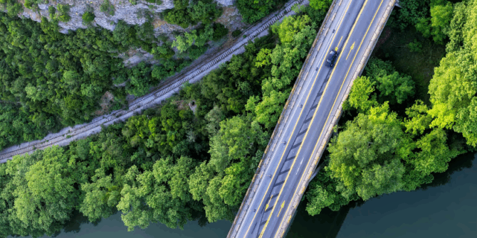 an arial photo of a bridge over a river, surrounded by forest